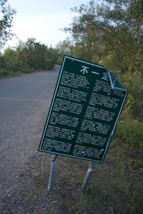 Bent roadside sign carrying a full Chinese essay